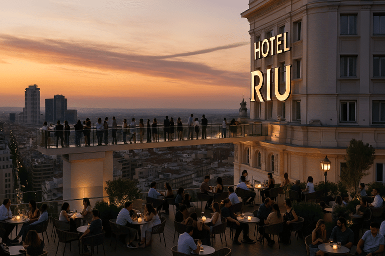 Terraza del Hotel Riu Plaza España al atardecer con clientes sentados y personas paseando sobre la pasarela de cristal con vistas a Madrid.