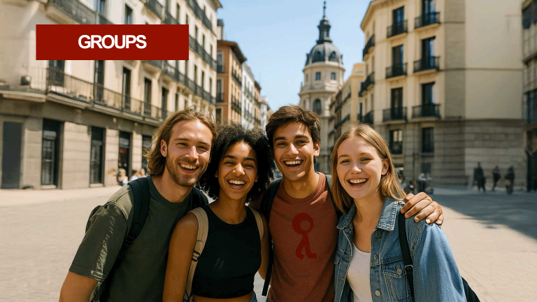 Group of four young friends smiling in a sunny street in Madrid.