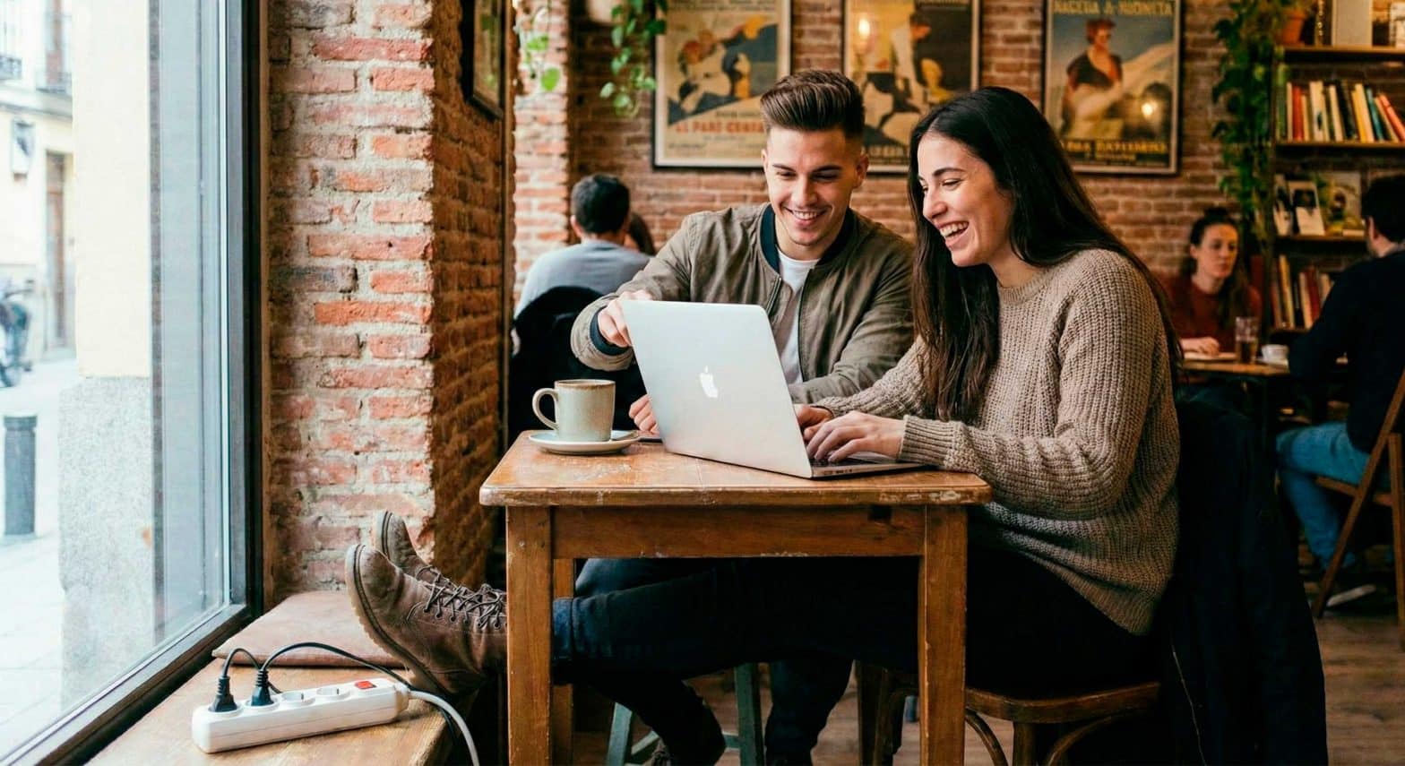 Personas teletrabajando con portátil en una cafetería de Malasaña con café y enchufe cerca.